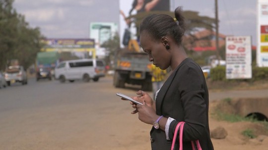 Woman&nbsp;wearing a blazer checks her mobile phone in the street.